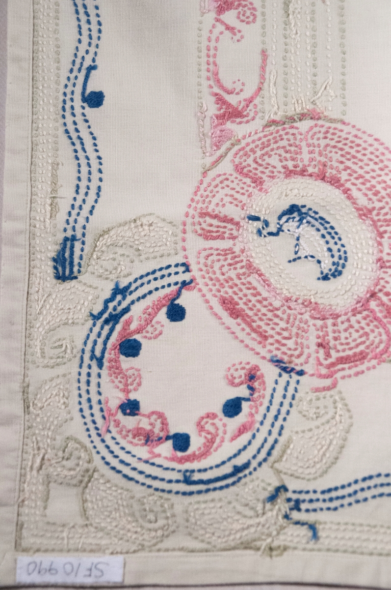 Bomullslerret, falda og brodert med attersting.