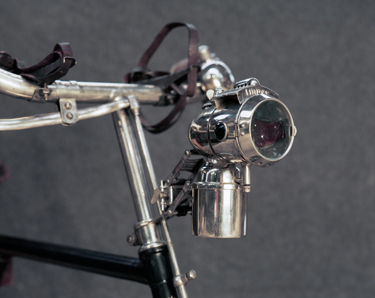 Herrcykel av typ upp-och-nertrampare (till skillnad från rundtrampare). Upp-och-nedgående pedaler med kedjor till baknavet som är en s.k. rullspärr enl. Birger Ljungströms konstruktion, patenterad 1892. Rullspärren ger frihjulsfunktion. De fram-och-återgående kedjorna ger baknavet en roterande rörelse genom två excentriska "drivskivor". Fem tryckluftsreglerade växlar. På styret finns två gummiblåsor dolda under metallhöjle. Luften leds med slangarna till ytterliggare två gummiblåsor placerade på segmenten vid tramporna. Broms på bakhjulet genom att de båda tramporna trycks ned och påverkar en hävarm som trycker två roterande koniska bromsklotsar mot bakdäcket. Senare modell hade s.k. skedbroms mot bakdäcket. Framhjulsbroms med s.k. skedbroms mot framdäcket. Fälgar och skärmar av trä.
Tillbehör: Verktygsväska, signalklocka, skylt med polisens ordningsnr, 6808.
