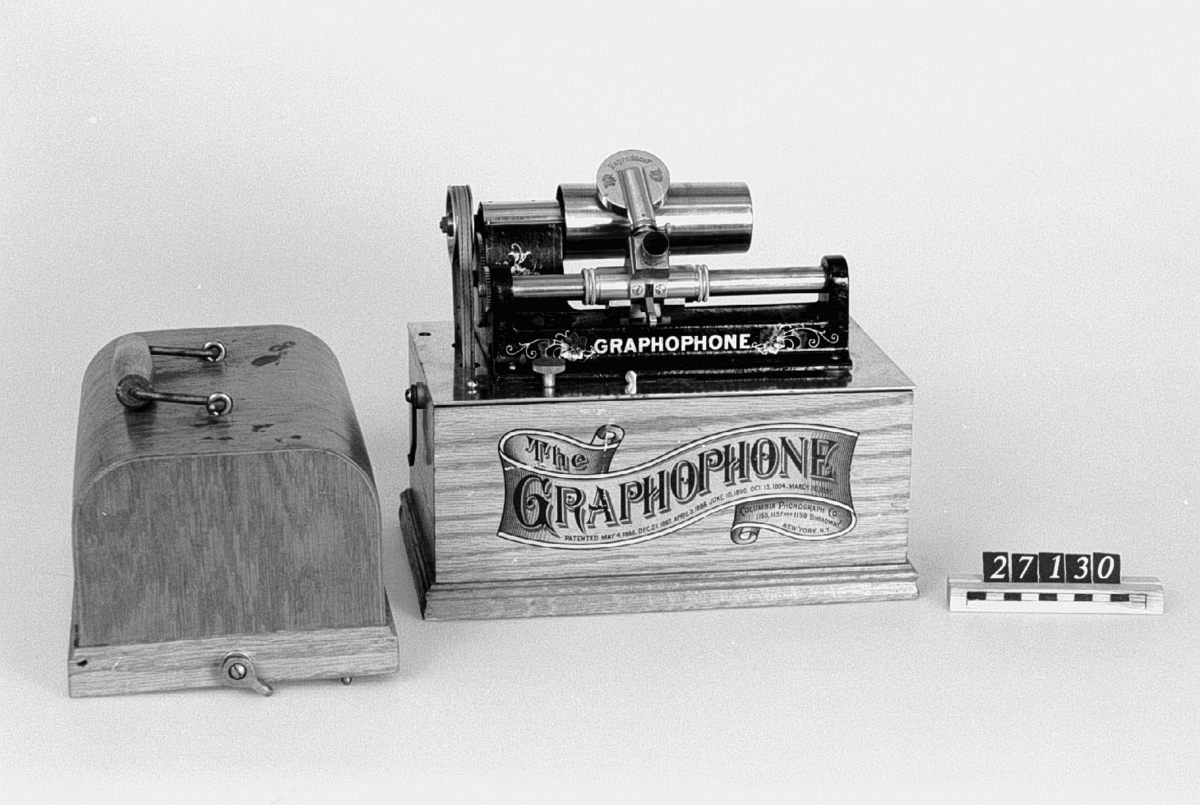 Fonograf, med svarvanordning. Avsedd för 5 tums vaxrullar, 120 varv/minut. Skylt: "The Graphophone patented May 4 1886 .... Mar 30 1897 Manufactured by the American Graphophone Company, New York, N.Y. Type HG 1216".
Tillbehör: Lösa delar: apparat, vev, ljuddosa för återgivning, ljuddosa för upptagning (båda i pappask), böjd tratt, huv av trä samt ytterhuv av brunt läder.