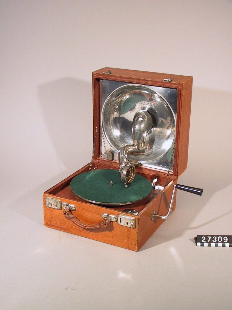 Resegrammofon, "Decca", med skålformad ljudtratt och ljudarm av aluminium på insidan av locket enligt engelskt patent år 1914. Med verk och dosa från Schweiz. Skylt i lådan: "Keith Prowse & Co Ltd. Branches all over London". Ljuddosan: "Dulcephone trade mark swiss made. For all gramophones. The New "Crescendo soundbox". Stämplat på ljudarmen: "Regd 631877 Patent 3033".