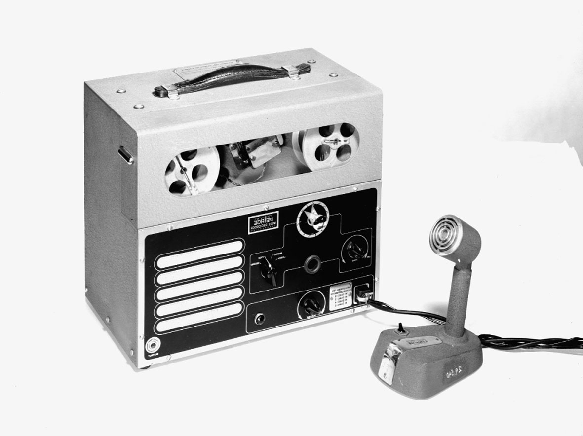 Trådspelare. Mikrofon och nättrafo separat. Förvaras i trälåda med bärhandtag. Tråddiktafonen är i 4 delar: 1 st. tråddiktafon, 1 st. bordsmikrofon (typ typ M 5040-2), 1 st. transformator och 1 st. trälåda. Tråddiktafonen har en 2 meter lång sladd för anslutning till transformatorn. Transformatorn har en 1 1/2 meter lång sladd för anslutning till elnätet. Bordsmikrofonen har en 4.8 meter lång sladd för anslutning till tråddiktafon. Lådans längd: 400 mm, bredd: 300 mm, höjd: 530 mm. Bordsmikrofonens längd: 140 mm, bredd: 95 mm, höjd: 190 mm. Tråddiktafonens längd: 340 mm, bredd: 195 mm, höjd: 290 mm. Transformatorns längd: 180 mm, bredd: 100 mm, höjd: 110 mm. Skylt: Bolinders tråd-diktafon M 4050-2.