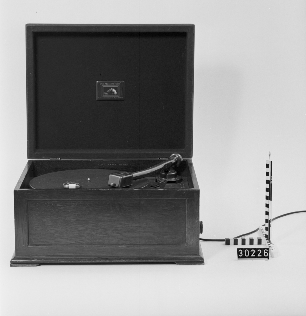 Grammofon, elektrisk, av trä. Grammofonverket är inbyggt i en trälåda, högtalaren är separat. På lådans baksida en varningsskylt: "Warning This set is for operation on AC. Mains Only. 50-60 Cycles for voltage range, see instruction Card".