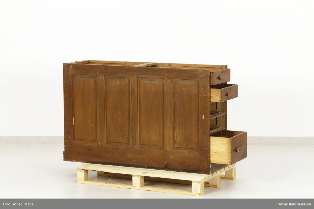 KLM 45471:1-2. Hurts, skrivbordshurts. Två stycken. Avlång hurts utan överdel. Av trä, ådringsmålad i ljusbrun kulör. Hurts :1 har på vardera kortsida en dörr med inbyggt lås. Inuti utrymmena diverse fack och hyllor. På ena långsidan en dubbeldörr med inbyggt lås. Utrymmet är indelat i två fack och åtta hyllplan. På några av hyllplanens främre kant är skrivet: Normal-skrivpapper, Skrivpapper 375x480, Postpapper 47 ark, Läskpapper 8 ark. Hurts :2 har på vardera kortsida utdragbara lådor, ett flertal saknas. Båda hurtsarna är försedda med spegeldörrar/väggar.