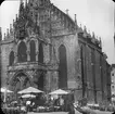 Skioptikonbild med motiv av marknad framför Die Frauenkirche i Nürnberg.
Bilden har förvarats i kartong märkt: Nürnberg IX. 1901.