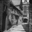 Skioptikonbild med motiv av man på gata vid äldre hus, invid kyrka i Oberwesel.
Bilden har förvarats i kartong märkt: Resan 1904. Oberwesel