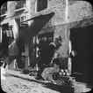 Skioptikonbild med motiv kvinna vid fruktstånd på gata i GRanada.
Bilden har förvarats i kartong märkt: Höstresan 1910. Granada 9. No 25. Text på bild: 