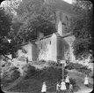 Skioptikonbild med motiv av lekande barn utanför stadsmuren, vid  St. Petrikyrkan i Rostock.
Bilden har förvarats i kartong märkt: Resan 1912. Rostock 4. Güstrow.. Text på bild: 