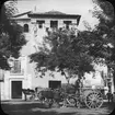 Skioptikonbild med motiv av hästar med lastade kärror utanför Casa de los Tiros, Granada.
Bilden har förvarats i kartong märkt: Höstresan 1910. Granada 9. N:7. Text på bild: 