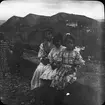 Skioptikonbild med motiv av kvinna med två flickor.
Bilden har förvarats i kartong märkt: Höstresan 1910. Granada. N:16. Text på bild: 