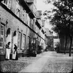 Skioptikonbild med motiv av två kvinnor utanför hus i Lübeck.
Bilden har förvarats i kartong märkt: Resan 1907. Lübeck 8. 1.