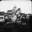 Skioptikonbild med motiv av vy över Diez med borgen.

Bilden har förvarats i kartong märkt: Resan 1908. Amberg. XXX. Text på bild: 