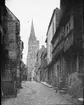 Skioptikonbild med motiv från gatan Rue de Cuisiners i Bayeux med katedralen i bakgrunden.
Bilden har förvarats i kartong märkt: Resan 1908. Bayeux 8. XI.