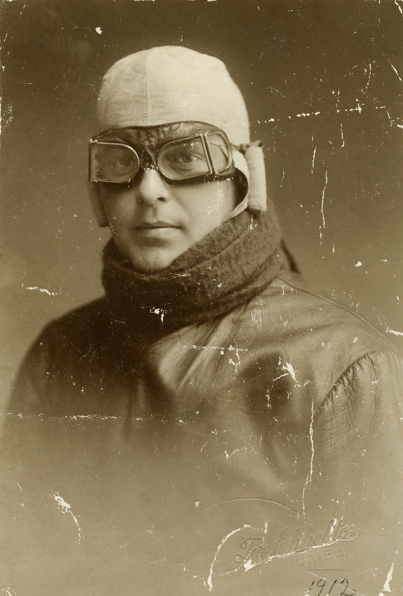 Olle Dahlbäck 1912, iklädd bruna skinnkläder, grön yllehalsduk och vit flyghuva.