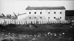 Ljusbild, fotografi från Nordiska arkitekturmötet på Gotland 1920. Äldre fabriksbyggnad i sten.