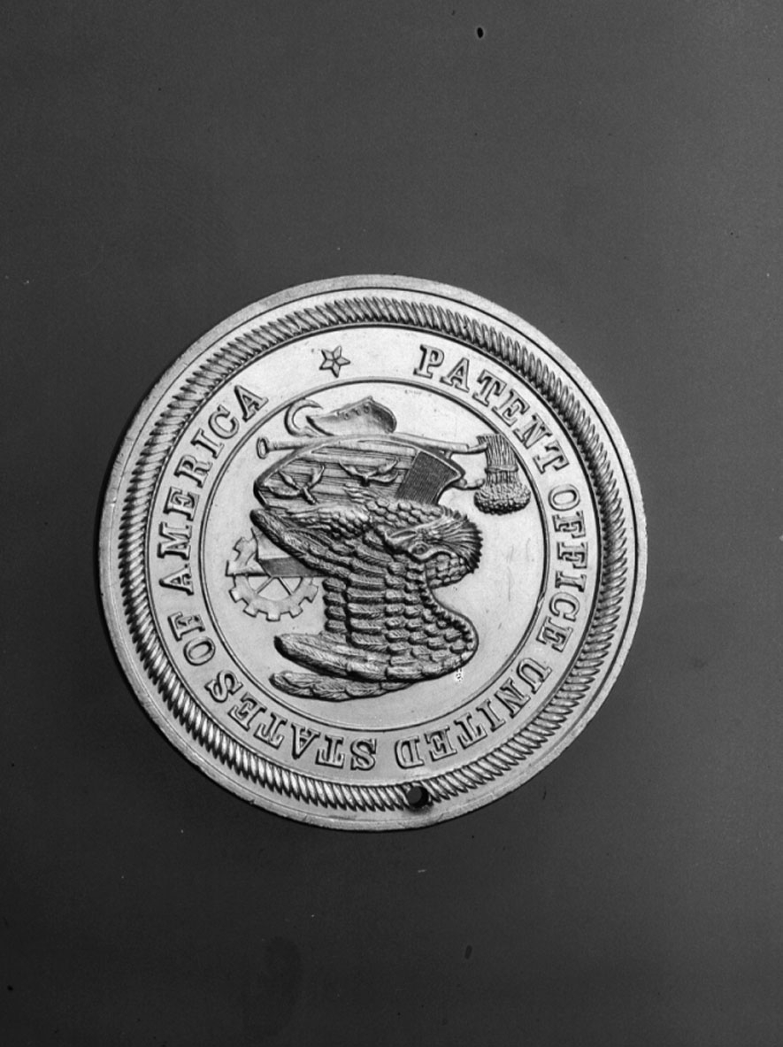 Har tillhört Gustaf de Laval. Slagen till minne av amerikanska patentverkets 100-årsjubileum år 1891. Åtsidan: Örn och diverse emblem med text runtom: "PATENT OFFICE UNITED STATES OF AMERICA". Frånsidan: "PATENT CENTENNIAL CELEBRATION, WASHINGTON APRIL 10. 1891". Tjocklek 40 mm.