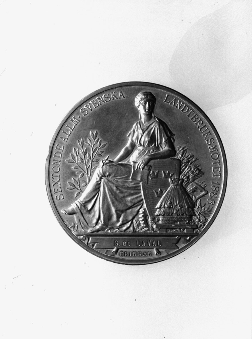 I brons slagen till minne av Sextonde Allm. Sv. Lantbruksmötet 1886. Tjocklek 5 mm. Tillägnad G. de Laval. I etui. Åtsidan: Vänster profil av Oscar II med text runtom: "OSCAR II SVERIGES OCH NORGES KONUNG". Frånsidan: Kvinnofigur och diverse emblem samt text: "SEXTONDE ALLM. SVENSKA LANDTBRUKSMÖTET 1886. G. DE LAVAL ERINRAN". Signerad: A. Lindberg.