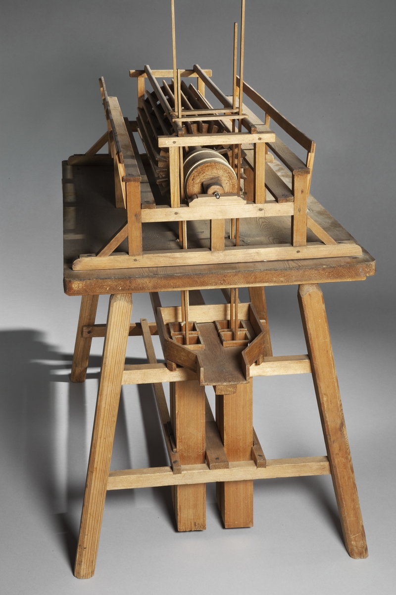 Modell av pumpinrättning, använd vid slussbyggnaden i Stockholm. Text på föremålet: "N:o 95. Modell på 4 pumpar med Tramphjul af Com. Polhem". I Jonas Norbergs förteckning från 1779 beskrivs modellen på följande sätt: "Modell på et annat slags Vattn Uppfordringsvärk, bestående af 4 stora Pumpar; som drefvos med et så stort tramphjul, at 30 man voro commenderade til dess bibehållande  i jämn gång. Af dessa 30 man, trampade ständigt 10 Man på hvardera sidan om hjulet, emedan 10 hvilade, som åter i deras ordning omväxlade med endera sidans arbetare. Detta Pumpvärk upfordrade en stor myckenhet vatn, och var nödvändigt i anseende til af små klappersten bestående botnen, hvarigenom en mängd av vatn insilade."