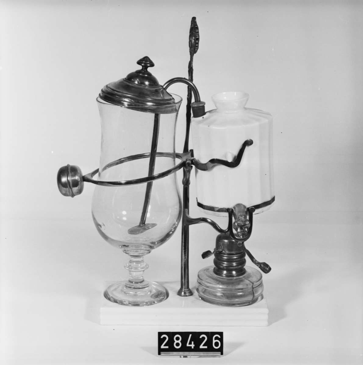 Kaffebryggningsapparat med automatisk släckning av spritlampan då brygden är färdig. Bestående av sju delar.
Malet kaffe läggs i den stora glasbehållaren och vatten fylls i porslinsbehållaren. Brännaren med lysfotogen tänds och vattnet hettas upp. Ångtrycket i porslinsbehållaren pressar ut det heta vattnet till glasbehållaren där det blandas med kaffet. När allt vatten är tömt ur porslinsbehållaren lättar den och ett lock faller över brännaren som då släcks. Porslinsbehållaren kallnar och suger tillbaka det färdigbryggda kaffet, sumpen blir kvar i glasbehållaren.