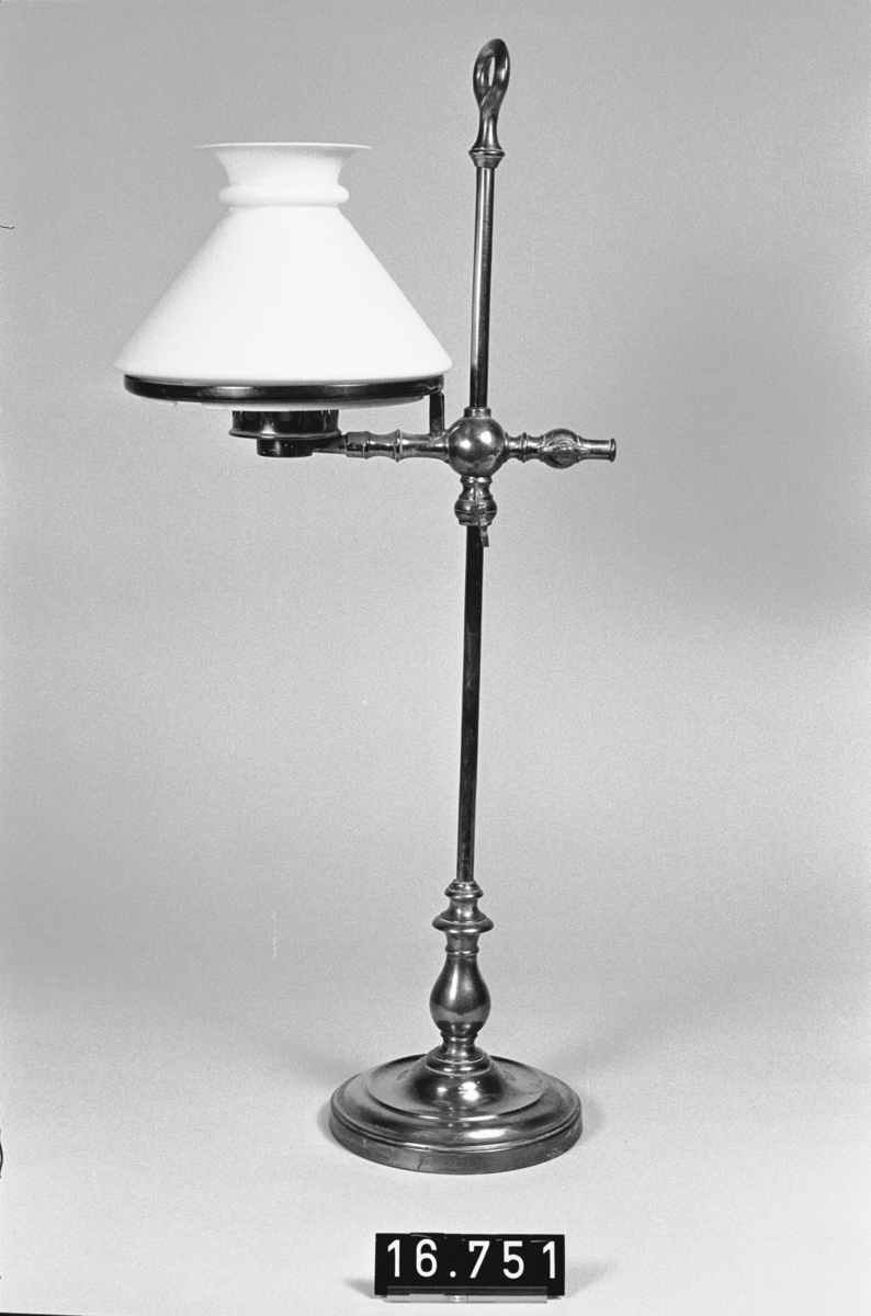 Bordslampa med höj- och sänkbar brännare av porslin samt lampkupa och kupring. Lampkupa: TM 18.136. En flisa borta ur kupans nedre hals. Lampglas saknas dock.
Tillbehör: Lösa delar: lampfot, kupring, lampkupa.