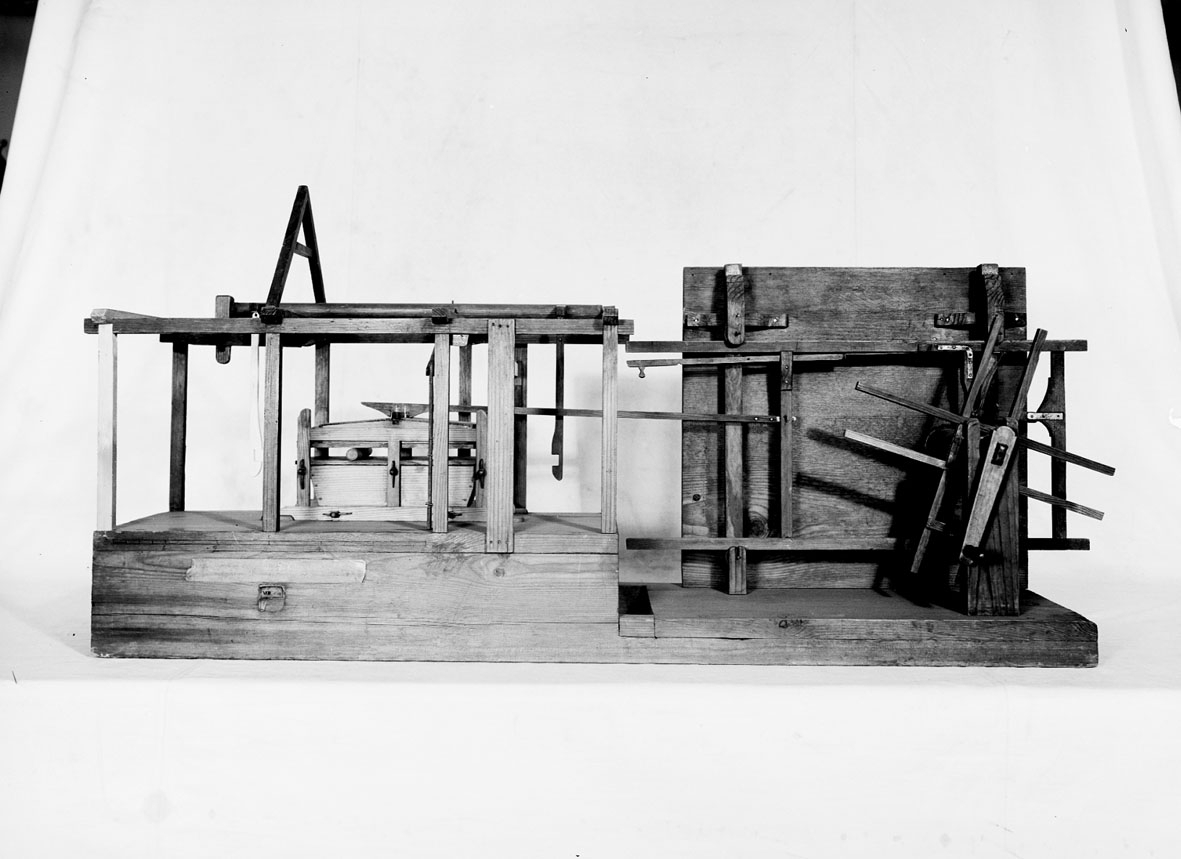 Modell av mjölkvarnshjul kombinerat med mangel. Text på föremålet: "XVII.E.12" . I Jonas Norbergs förteckning från 1779 beskrivs modellen på följande sätt: "Modell på en rörelse, som appliceras til en Mjöhl=Qvarn, och hvarmedels man genom en kugges tilsats på hjulaxeln, kan utan hinder i maningen, tillika draga en mangel, eller annat dylikt# af undertecknad."