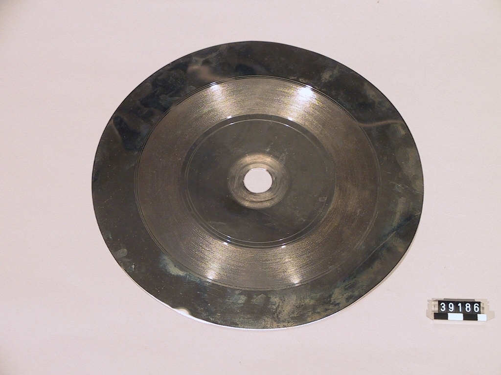 Matris, s.k. "fadermatris" vid tillverkning av grammofonskivor. Galvaniskt framställd nickelplåt. Centrumhål diameter: 20 mm, höjd: 0.3 mm.