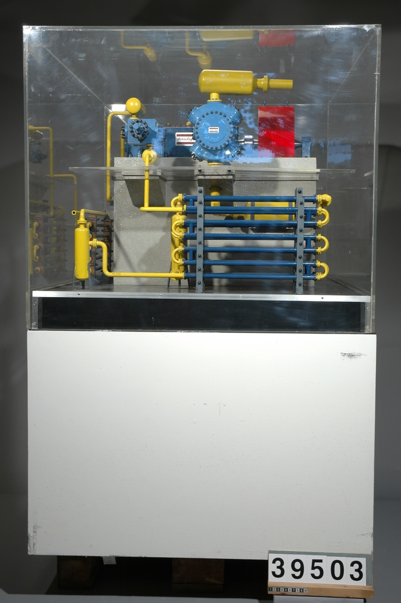 Modell av fyrstegs syntetgasmaskin med horisentalla cylindrar. Vevaxel med fyra vevar och slaglängden 200 mm. Första stegets cylinderdiameter är 255 mm. Maskinen är avsedd att höja inkommande gasens tryck från 17 bar till 326 bar. Gasflödet är 6680Nm3/h, varvtalet 368 rpm och axeleffekt behovet 440 kw. Syntetgasen som komprimeras kan tänkas förekomma i någon kemisk industri t.ex. i samband med plastråvarans framställning.
Tillbehör: Podie och plexiglashuv.