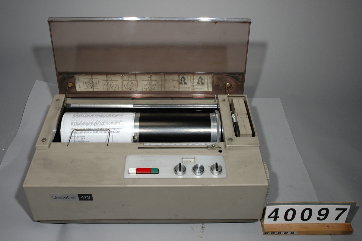 Stencilapparat, Gestetner 460s, 200W. 46kg. L 425mm B 490 H 450 Skåp av metall för div. tillbehör med tre lådor, Mått: 410bx590lx800h, vikt inkl innehåll: 54 kg. Innehåll: 7 st paket stenciler, 17 st tuber grå färg och rengöringsvätskor 1st instuktionsbok för Stencilerings apparat Gestetner 466. Ca 150st påbörjade stenciler m text "Tonårsbrevet" Skåp av plywood vari man förvarade färdiga och infärgade stenciler, grått, tomt. 8kg Bredd: 570 mm, längd: 175 mm, höjd: 573 mm. Brännare, Gestetner 473, No F92426, 200W, tysk, ljusbrun plast. vikt 23kg Bredd: 390 mm, längd: 690 mm, höjd: 225 mm.