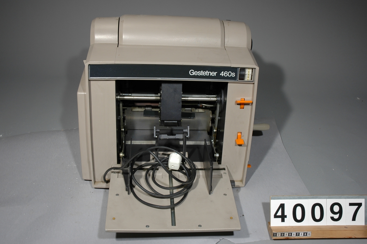 Stencilapparat, Gestetner 460s, 200W. 46kg. L 425mm B 490 H 450 Skåp av metall för div. tillbehör med tre lådor, Mått: 410bx590lx800h, vikt inkl innehåll: 54 kg. Innehåll: 7 st paket stenciler, 17 st tuber grå färg och rengöringsvätskor 1st instuktionsbok för Stencilerings apparat Gestetner 466. Ca 150st påbörjade stenciler m text "Tonårsbrevet" Skåp av plywood vari man förvarade färdiga och infärgade stenciler, grått, tomt. 8kg Bredd: 570 mm, längd: 175 mm, höjd: 573 mm. Brännare, Gestetner 473, No F92426, 200W, tysk, ljusbrun plast. vikt 23kg Bredd: 390 mm, längd: 690 mm, höjd: 225 mm.