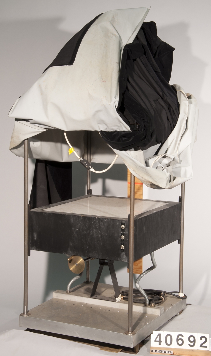 "Althins projektor", episkop för projicering av tredimensionella föremål. På fyrbent stativ av brösthöjd, överst med lamphus, proj. objektiv och spegel. På stativets halva höjd en "ljuslåda" med mjölkglasskiva. Stativet omsvept av svart, ljustätt skynke. Ljuslådan: 550 x 450 mm. Max: längd: 700 mm, bredd: 650 mm, höjd: 1700 mm.