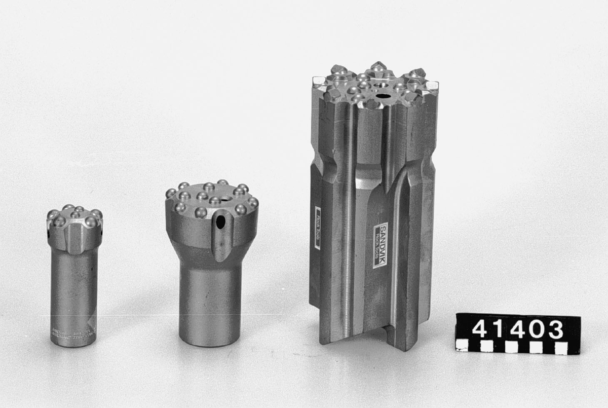 Tre borrkronor: 
En stor, diameter: 100 mm, längd: 225 mm, vikt 9, 6 kg. Märkt: Sandvik Rock Tools. 
En mindre, diameter: 79 mm, längd: 130 mm, vikt 2,4 kg. Märkt: Sandvik Coromant R 32-76-9/1, 7733-6676-40. Denna är även märkt med etikett, som har lossnat "DP Dual/Property". 
Den tredje, diameter: 45 mm, längd: 114 mm, vikt: 0,7 kg. Märkt Sandvik Coromant R28-45-6/4 7739-0545-40.