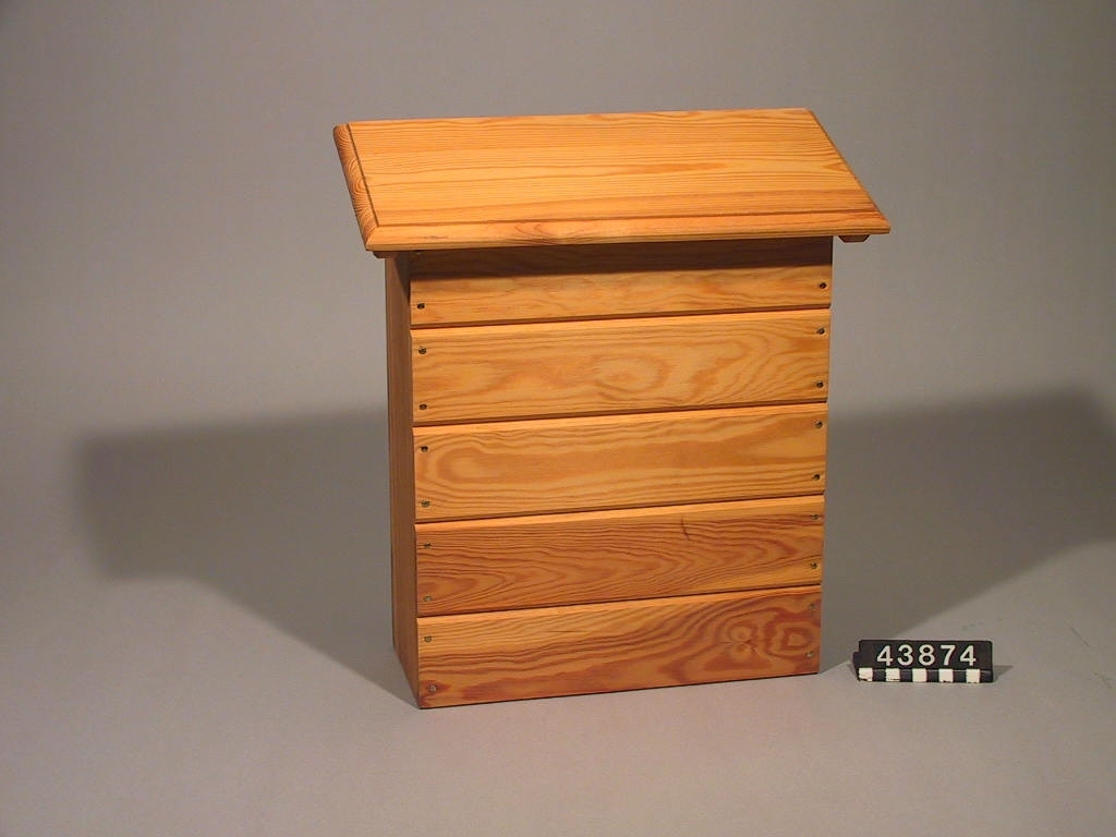 Postlåda av trä med genomskinlig botten i plexiglas. Den genomskinliga botten medför att problem med tvestjärtar och myror i lådan elimineras eftersom dessa är ljusskygga och bottnen släpper in ljus.