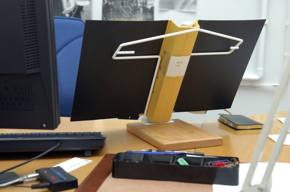 Pärmstöd som kan användas för både liggande och stående A4 pärmar. Pärmstödet består av en bockad trådställning som utgör hållare och stöd för pärmar. Stödet ger en lutning på pärmen som är gynnsam för den som arbetar länge med en pärm.