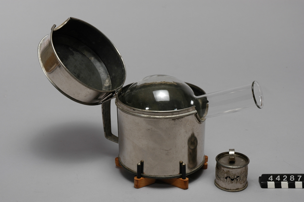 Kaffepumpa av glas och metall för kokning av kaffe, består av en plåtburk med ett kolvglas i som ska ställas på vedspisen, även litet lock till pipen, från 1921, slitet skick.