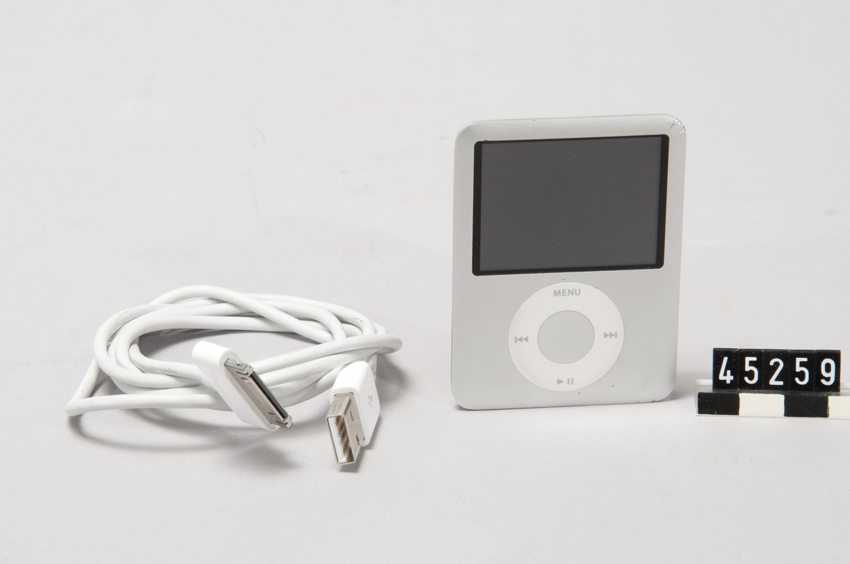 Mp3-spelare iPod Nano 4GB Model A1236 ser no 5U8229COYOP Designed by Apple in California. Assembled in China. För anslutning 5-30V likström max 1A  Enheten fylld med 3,5 GB ljudfiler Tillhörande anslutningskabel till dator, för USB-uttag