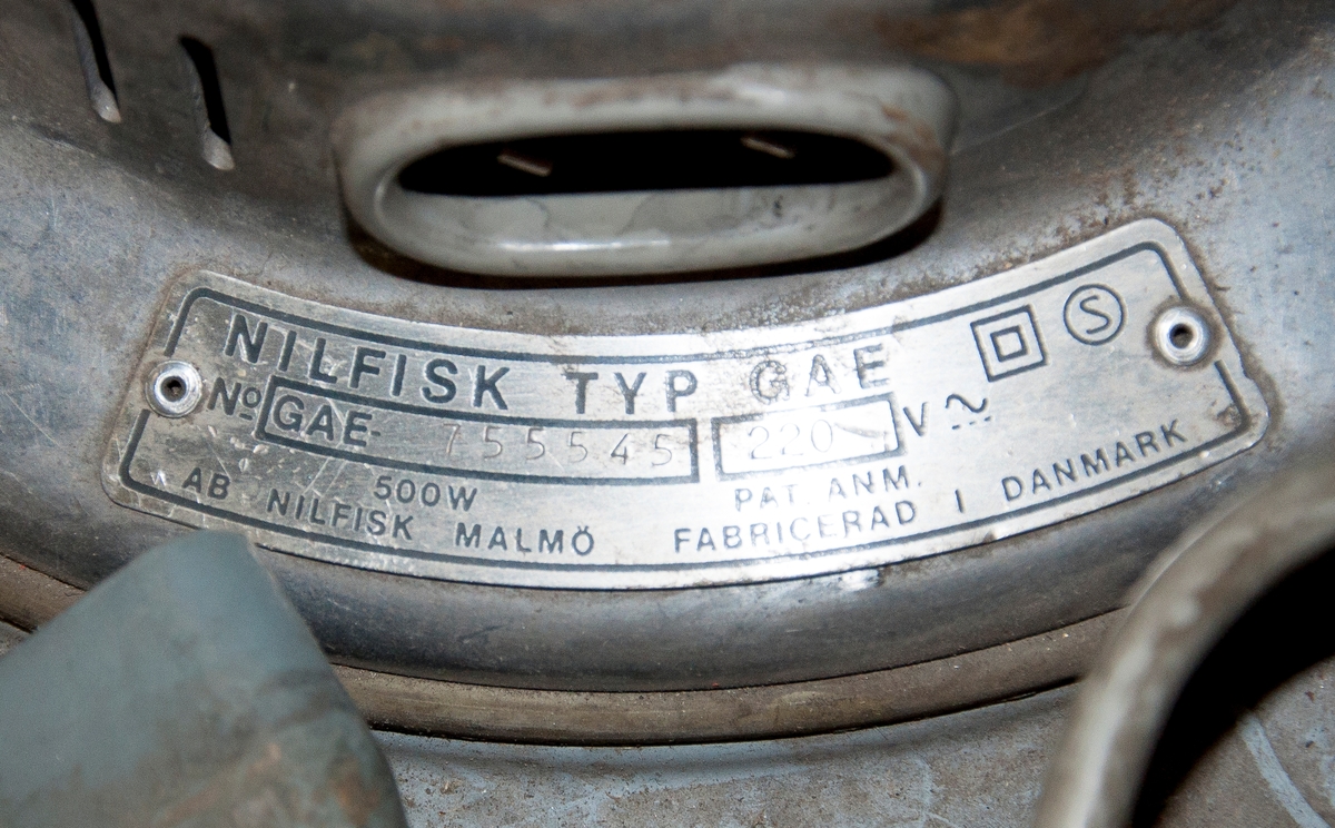 Industridammsugare Nilfisk typ GA73-7111. 
Utformad som en behållare på ställning med hjul, utrustad med tre motorer à  500 W. Motorerna är av typen GAE med serienummer 755543, 755544, 755545, ...  
Maskinen är märkt med dekal: "NBM Hydraulic, kopplingar, slangar, Karlbergs strand Solna". Även försedd med klistermärke för kopiator av märket Minolta samt parkeringstillstånd för Stockholms kommun, giltigt 1986.