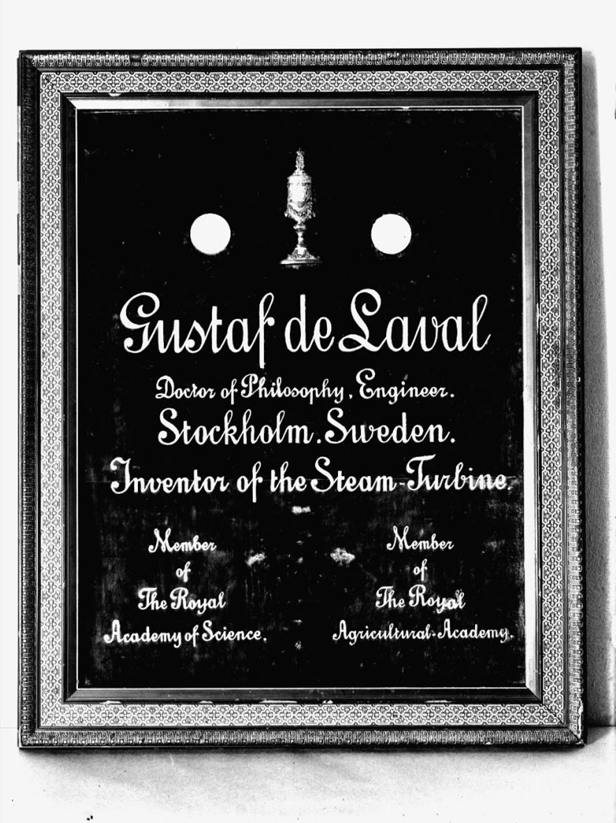 Tavla med mässingsbokstäver på röd sammet: "Gustaf de Laval Doktor of Philosophy, Engineer, Stockholm, Sweden. Inventor of The Steam Turbine. Member of The Royal Academy of Science. Member of the Royal Agricultural Academy".