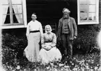 Familjegrupp tre personer.
Bostadshus i bakgrunden.
Makarna Pettersson med dottern Nelly.
Bilden tagen 1920 eller tidigare.