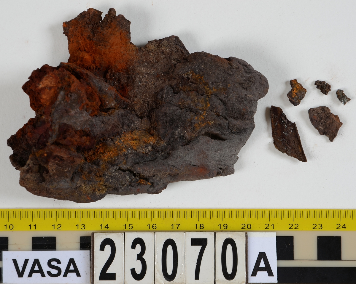 Sko.
Inuti skorna hittades även fragment från olika textilier som ursprungligen varit ett par strumpor. Idag sitter ett stickat fragment av ull fast i vänsterskon (23070) med avigsidan uppåt. I fyndet finns även en mängd lösa stickade fragment som idag är mycket korroderade och vissa helt mineraliserade av järn vilket har gjort textilen stenhård och därmed oerhört skör (23070a-c). Utifrån minskningar som några små fragment har så har det varit möjligt att rekonstruera strumpans tå. Genom att pussla ihop fragmenten som ursprungligen har suttit ihop har det på så vis gått att avgöra hur strumpans tå har varit konstruerad. Då textilen är så fragmentarisk är det inte möjligt att avgöra hur resten av strumpan har sett ut eller varit konstruerad. Däremot så finns det fragment av ett kypertvävt tyg av ull som på vissa ställen ligger dubbelt med det stickade 23070c). Ett av dessa fragment har stelnat i formen så som den suttit på fotens främre del inuti skon. Detta fragment täcker delvis det stickade tyget och har dessutom spår av kaststygn längs en kant. Så som det vävda tyget är placerat på det stickade tyget pekar på att man använt det som lagningslappar till sina stickade strumpor. 
I fyndet finns det även korroderade järnklumpar, ett tuskaftsvävt tyg av ull och rester av ett grovt bastfibergarn och två mindre läderfragment (23070d-f). Det är möjligt att även dessa har tillhört strumpan och/eller skon.

För mer detaljerad information från textildokumentationen (år 2022) se länkade filer.

Skodokumentation 2022:
Ovanläder. Tillverkad i getskinn av god kvalitet. Hör ihop med fyndnummer 23069 (Yngves skor). Tillverkades på en rak läst och bars på vänster fot. Inga dekorationer Det finns stygnhål som visar att det funnits invändiga förstärkningar (men förstärkningslappen saknas). Det finns delaminering men inga lagningar.
För mer information, se Länkade filer: Uppritning

Text in english:
This is the upper of a shoe of more “extreme fashion”, made of goatskin leather of good quality, probably made on a straight last and worn of the left foot, with no decorative features. The upper couples with 23069, together composing Yngve’s shoes. There are internal reinforcements missing from the upper and delamination, there are no repairs.
For more information, go to Länkade filer: Uppritning