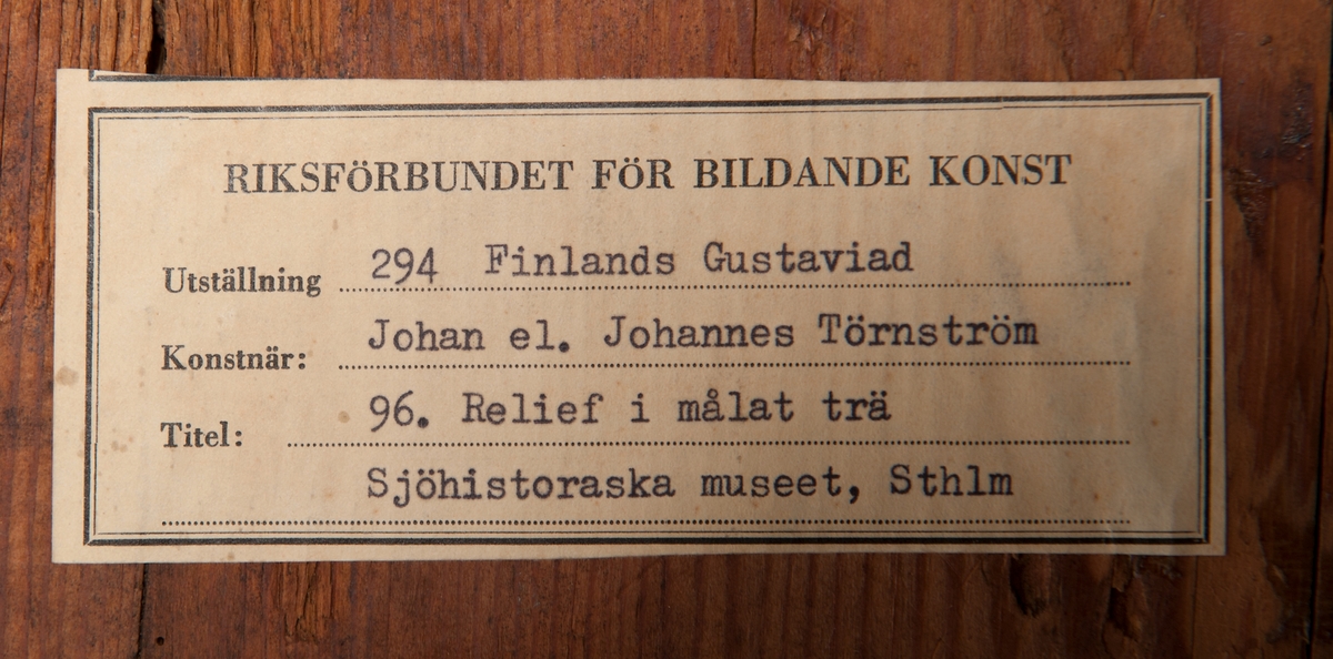 Medaljong, antikiserat kvinnohuvud, enligt uppgift föreställande grevinnan Ehrenswärds huvud. Röd på blågrön botten med oval röd kant.