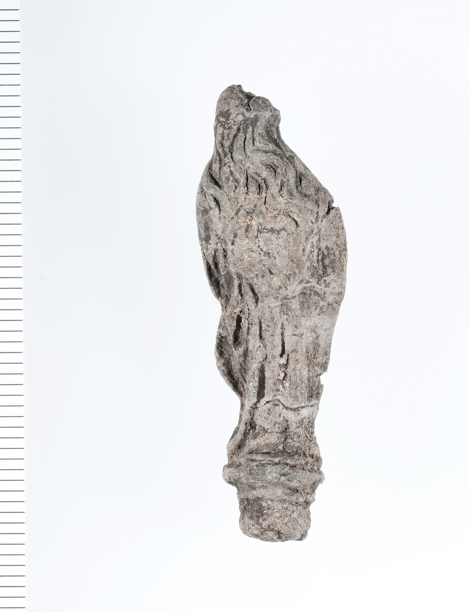 Forseggjort helfigur av en stående madonna som holder noe i armene. Motivet er noe slitt men fine detaljer i hår og klesdrakt er fortsatt tydelige. 