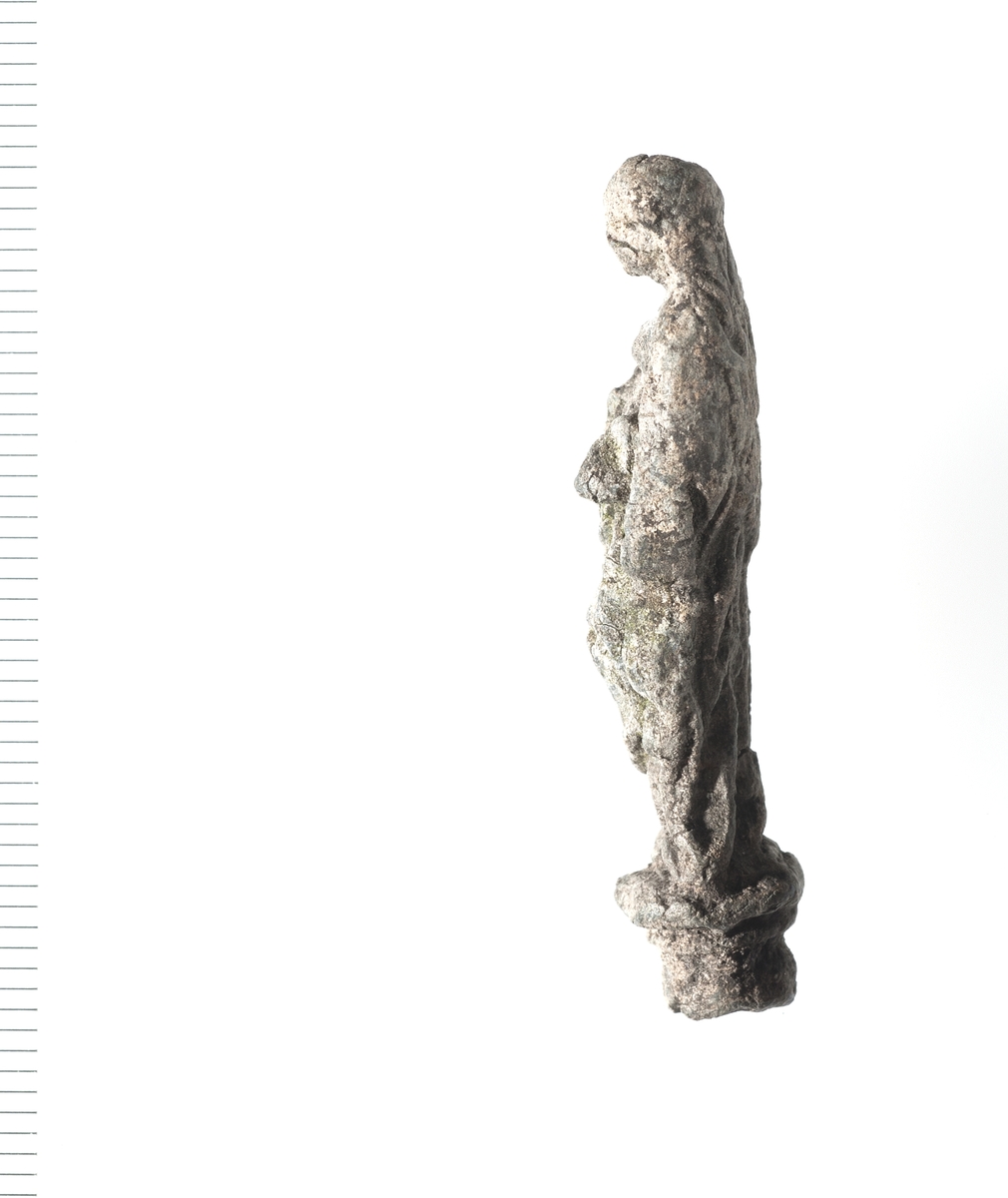 Forseggjort helfigur av en stående madonna som holder noe i armene. Motivet er noe slitt men fine detaljer i hår og klesdrakt er fortsatt tydelige. 