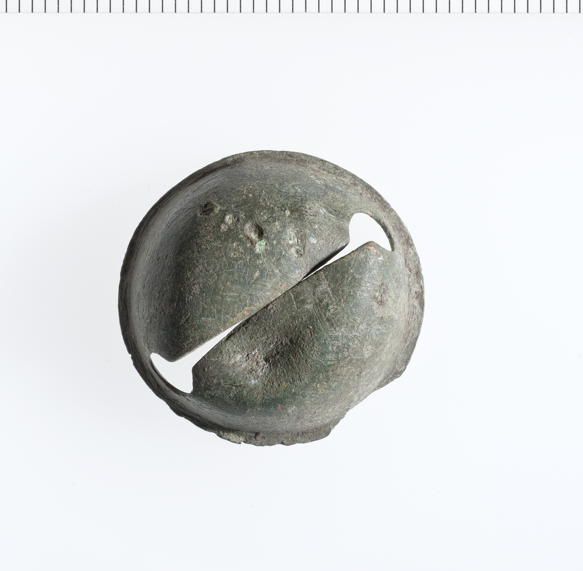 Rund og nesten intakt halvkuleformet halvpart av en liten bjelle, med en avrettet kant og et snitt i midten på ca 20mm. 