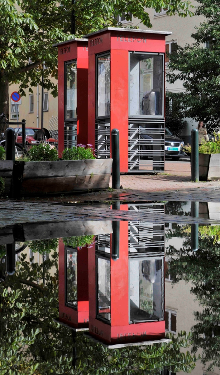 This is the story of how Norway’s most important conversation-space was designed by a young, freshly graduated man from Bergen.

“Norwegian architects are hereby invited…”
In the autumn of 1932, Oslo Telefonanlegginitiated an architectural competition. Finally, Oslo would get its own telephone booth. The city had had so called “talking-stations” from 1885, which in turn were overtaken by automatic telephones 
 only available at selected Narvesen kiosks. The state 
was of the opinion that now was the time to offer the public a better service; public telephone booths open 24/7, like the ones they already had in Sweden and England. But what would they look like, these new telephone booths? What considerations would it
 be necessary to take when designing it? The telegraph board developed a detailed list of demands and restraints: “The booth is intended to be placed outside on the streets and squares and need to be designed so that snow and ice does not hinder the opening and closing of the doors,” they wrote. “To prevent vandalism, theft, uncleanliness etc. inside the booth, it needs to be designed so that from all angles one may see what is going on in there.” Additionally, it would need to withstand storms and bad weather, and “preferably also being whipped by rain mixed with seawater” 

This was not all: The appearance would have to be «pleasing». The booth also needed to be movable, so that it could be taken in to be serviced at Telegrafverket’s main workshops. The reqired material was iron, and the surface was to be spray painted  preferably using car-body paint. There was a requirement for “a writing shelf, a pack shelf, and a suitable place for the telephone catalogue.” Also, there would need to be an illuminated TELEFON  sign, easily visible from all four angles. The total cost for each booth should not exceed 1000 kroner. The first prize for coming up with such a product was 800 kroner.

“Norwegianarchitects are hereby invited to partake in a competition for the design of a telephone booth…”  

The man with the solution
«At some point in 1932, Georg Fredrik sat at a party in Bergen. Maybe he felt a bit lost and forgotten as he often had throughout his life. He retreated to a quiet corner, took out a pencil and strted doodling on a matchbox.  According to my mother, this was how the telephone booth came into being.” In the book “Norges lille røde  historien om telefonkiosken,” Lars Fasting describes his father, the man who is far less known than the iconic architctural structure he left behind. Georg Fredrik Fasting was from Bergen, born into a family of working people and smallholders. One unusual facet of Georg Fredrik was that he was born without ears. His mother made sure he learnt to speak, read and write, 
ut Lars Fasting indicates that his father would seek refuge in drawing when the social challenges became too much to bear. And in the end drawing became his profession. In 1924 he secured a guarantor for a student loan, and started studying to become an a
rchitect at the NTH. Throughout the 1930s he entered several architectural competitions, with drafts produced, according to his son, “after work and in the late hours of the night.”

His efforts were not wasted. Out of 93 entries, with names such as “Flirt”, “Brrr”, “Ring” and “Amor”, the jury selected Fasting’s submission, “RIKS” as the new telephone booth: “The draft shows a strikingly simple solution to the task, technically as well as aesthetically well worked out.”

Taut and provident
Simple and aesthetc are the keywords here. Fasting had designed a booth pointing towards the future, and to modernism. Just how modern it was can be seen by comparing RIKS to the British telephone booth, also designed in the interwar-era. While the British version with it classicistic style is looking back to the heyday of the empire, Fasting’s booth is progressive and functionalistic. Like most Norwegian architects, Fasting broke with the classicistic style of architecture after the Stockholm-exhibition in 1930. “After it, almost all buildings erected in Norway until the German invasion in 1940, were in the functionalistic architectural style,” writes senior curator of architecture at the Norwegian National Museum, Ulf Grønvold, in the book, “Den lille røde”.“TheNorwegian booth is a piece of functionalistic architecture, an asymmetric composition with its roof slab overhanging the word TELEFON, in bold sans seraph lettering,”concludes Ulf Grønvold.

Fashionably red
And it was red. Fasting chose a colour which was part of the modern palette. “A bright red colour, but not as shiny as a signal red, the character of the colour places it among the fashionable colours within functionalism,” states paintings conservator and researcher in NIKU (Norwegian Institute for Cultural Heitage Research), Jon Brænne. In his opinion, Fasting went for visibility without making the booth stand out too much from its surroundings. The original colour was in use up to around 1950, when it changed to signal red. Towards the end of the 1970s the clour was again adjusted towards today’s orangey red.

The design, however, has not changed. RIKS is eighty years and still looks remarkably good. That’s what makes Fasting’s telephone booth a classic  even before it was added to DOCOMOMO’s list over moden icons of design. For Telenor, the telephone booth has served as a pathway into the hearts of the public. For many, Telenor (Televerket) was synonymous with exactly this telephone booth, because this was where one would go to place a call. Having a home
phone was not common until the 1980s. As such the red box became part of the Norwegian everyday and consciousness. The symbol- and publicity value of this is hard to evaluate, but in 2007 it was time to give honour where honour was due, Telenor, in consul
tation with the Directorate for Cultural Heritage, decided to preserve 100 telephone booths for all eternity.

And what about Georg Fredrik Fasting? What happened to him? At the age of 56 an entry in his diary states: «I CAN HEAR». As the first person in th world he had undergone an operation where he had ear canals constructed and eardrums fitted. For the rest of his life, the man behind Norway’s own telephone booth could answer the telephone himself.

Source: Norges lille røde historien om telefonkiosken (2007), issued by The Norwegian Telecom Museum and Telenor Cultural Heritage.