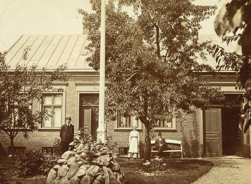 Vykort till Fru Kristin Gullberg Ahlgatan Trälleborg, hus på norregatan 35, kvarteret Nordpolen hus å tomt nummer 13 (196), foto från öst mot väst omkring år 1900, i förgrunden förgårdsträdgård åt Norregatan, på bilden ägaren lantbrukare Anders Olsson, förut ägare av gården nr. 1 Villie Lilla Slågarp. Dottern Lydia gift med byggnadsingenjör Ragnar Roslund i Trelleborg. Sonen Albert Otto Weige civilingenjör hos ASEA i Stockholm,9324