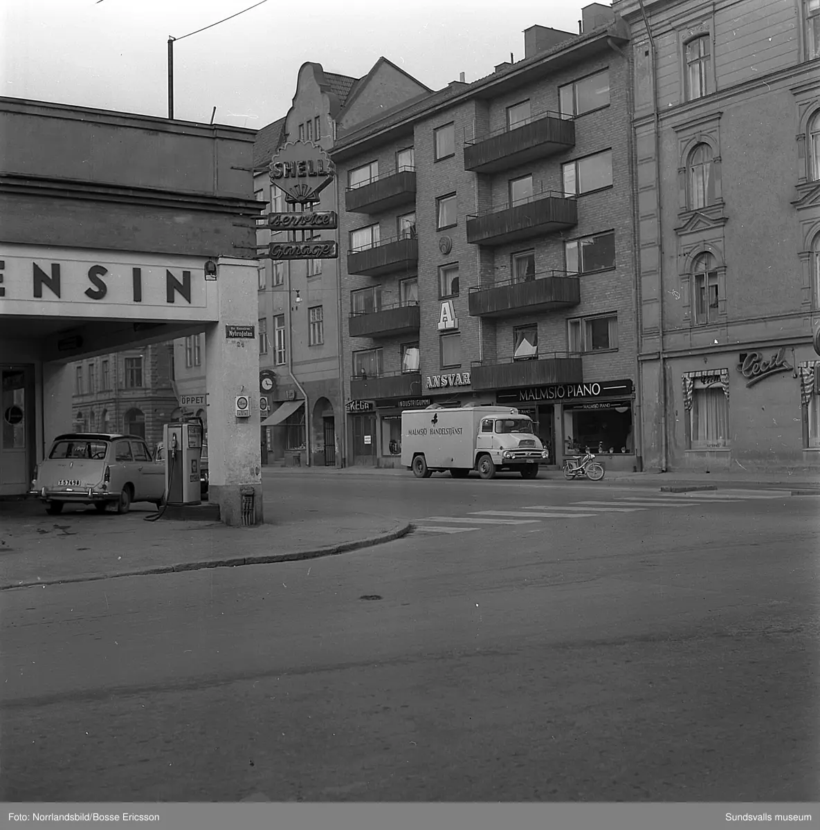 Gatuvyer i korsningen Köpmangatan-Nybrogatan med Shellmacken i hörnet, Cecil, Malmsjö piano med flera butiker.
