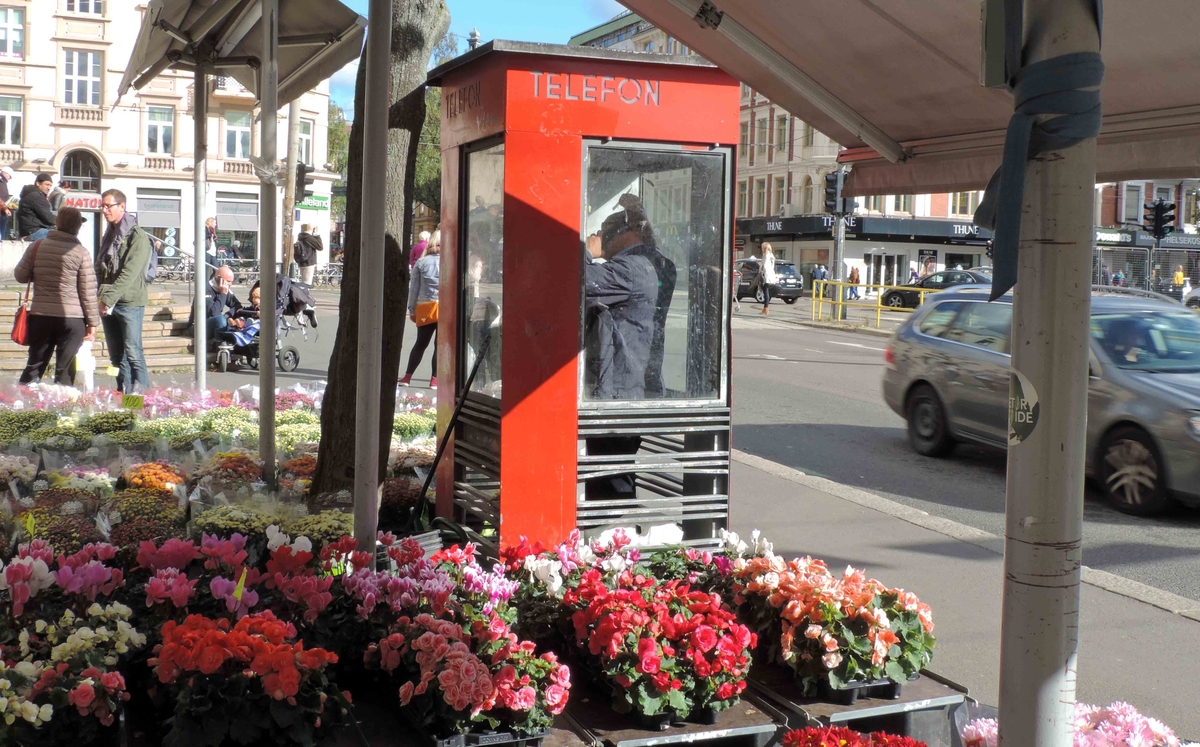 This is the story of how Norway’s most important conversation-space was designed by a young, freshly graduated man from Bergen.

“Norwegian architects are hereby invited…”
In the autumn of 1932, Oslo Telefonanlegginitiated an architectural competition. Finally, Oslo would get its own telephone booth. The city had had so called “talking-stations” from 1885, which in turn were overtaken by automatic telephones 
 only available at selected Narvesen kiosks. The state 
was of the opinion that now was the time to offer the public a better service; public telephone booths open 24/7, like the ones they already had in Sweden and England. But what would they look like, these new telephone booths? What considerations would it
 be necessary to take when designing it? The telegraph board developed a detailed list of demands and restraints: “The booth is intended to be placed outside on the streets and squares and need to be designed so that snow and ice does not hinder the opening and closing of the doors,” they wrote. “To prevent vandalism, theft, uncleanliness etc. inside the booth, it needs to be designed so that from all angles one may see what is going on in there.” Additionally, it would need to withstand storms and bad weather, and “preferably also being whipped by rain mixed with seawater” 

This was not all: The appearance would have to be «pleasing». The booth also needed to be movable, so that it could be taken in to be serviced at Telegrafverket’s main workshops. The reqired material was iron, and the surface was to be spray painted  preferably using car-body paint. There was a requirement for “a writing shelf, a pack shelf, and a suitable place for the telephone catalogue.” Also, there would need to be an illuminated TELEFON  sign, easily visible from all four angles. The total cost for each booth should not exceed 1000 kroner. The first prize for coming up with such a product was 800 kroner.

“Norwegianarchitects are hereby invited to partake in a competition for the design of a telephone booth…”  

The man with the solution
«At some point in 1932, Georg Fredrik sat at a party in Bergen. Maybe he felt a bit lost and forgotten as he often had throughout his life. He retreated to a quiet corner, took out a pencil and strted doodling on a matchbox.  According to my mother, this was how the telephone booth came into being.” In the book “Norges lille røde  historien om telefonkiosken,” Lars Fasting describes his father, the man who is far less known than the iconic architctural structure he left behind. Georg Fredrik Fasting was from Bergen, born into a family of working people and smallholders. One unusual facet of Georg Fredrik was that he was born without ears. His mother made sure he learnt to speak, read and write, 
ut Lars Fasting indicates that his father would seek refuge in drawing when the social challenges became too much to bear. And in the end drawing became his profession. In 1924 he secured a guarantor for a student loan, and started studying to become an a
rchitect at the NTH. Throughout the 1930s he entered several architectural competitions, with drafts produced, according to his son, “after work and in the late hours of the night.”

His efforts were not wasted. Out of 93 entries, with names such as “Flirt”, “Brrr”, “Ring” and “Amor”, the jury selected Fasting’s submission, “RIKS” as the new telephone booth: “The draft shows a strikingly simple solution to the task, technically as well as aesthetically well worked out.”

Taut and provident
Simple and aesthetc are the keywords here. Fasting had designed a booth pointing towards the future, and to modernism. Just how modern it was can be seen by comparing RIKS to the British telephone booth, also designed in the interwar-era. While the British version with it classicistic style is looking back to the heyday of the empire, Fasting’s booth is progressive and functionalistic. Like most Norwegian architects, Fasting broke with the classicistic style of architecture after the Stockholm-exhibition in 1930. “After it, almost all buildings erected in Norway until the German invasion in 1940, were in the functionalistic architectural style,” writes senior curator of architecture at the Norwegian National Museum, Ulf Grønvold, in the book, “Den lille røde”.“TheNorwegian booth is a piece of functionalistic architecture, an asymmetric composition with its roof slab overhanging the word TELEFON, in bold sans seraph lettering,”concludes Ulf Grønvold.

Fashionably red
And it was red. Fasting chose a colour which was part of the modern palette. “A bright red colour, but not as shiny as a signal red, the character of the colour places it among the fashionable colours within functionalism,” states paintings conservator and researcher in NIKU (Norwegian Institute for Cultural Heitage Research), Jon Brænne. In his opinion, Fasting went for visibility without making the booth stand out too much from its surroundings. The original colour was in use up to around 1950, when it changed to signal red. Towards the end of the 1970s the clour was again adjusted towards today’s orangey red.

The design, however, has not changed. RIKS is eighty years and still looks remarkably good. That’s what makes Fasting’s telephone booth a classic  even before it was added to DOCOMOMO’s list over moden icons of design. For Telenor, the telephone booth has served as a pathway into the hearts of the public. For many, Telenor (Televerket) was synonymous with exactly this telephone booth, because this was where one would go to place a call. Having a home
phone was not common until the 1980s. As such the red box became part of the Norwegian everyday and consciousness. The symbol- and publicity value of this is hard to evaluate, but in 2007 it was time to give honour where honour was due, Telenor, in consul
tation with the Directorate for Cultural Heritage, decided to preserve 100 telephone booths for all eternity.

And what about Georg Fredrik Fasting? What happened to him? At the age of 56 an entry in his diary states: «I CAN HEAR». As the first person in th world he had undergone an operation where he had ear canals constructed and eardrums fitted. For the rest of his life, the man behind Norway’s own telephone booth could answer the telephone himself.

Source: Norges lille røde historien om telefonkiosken (2007), issued by The Norwegian Telecom Museum and Telenor Cultural Heritage.