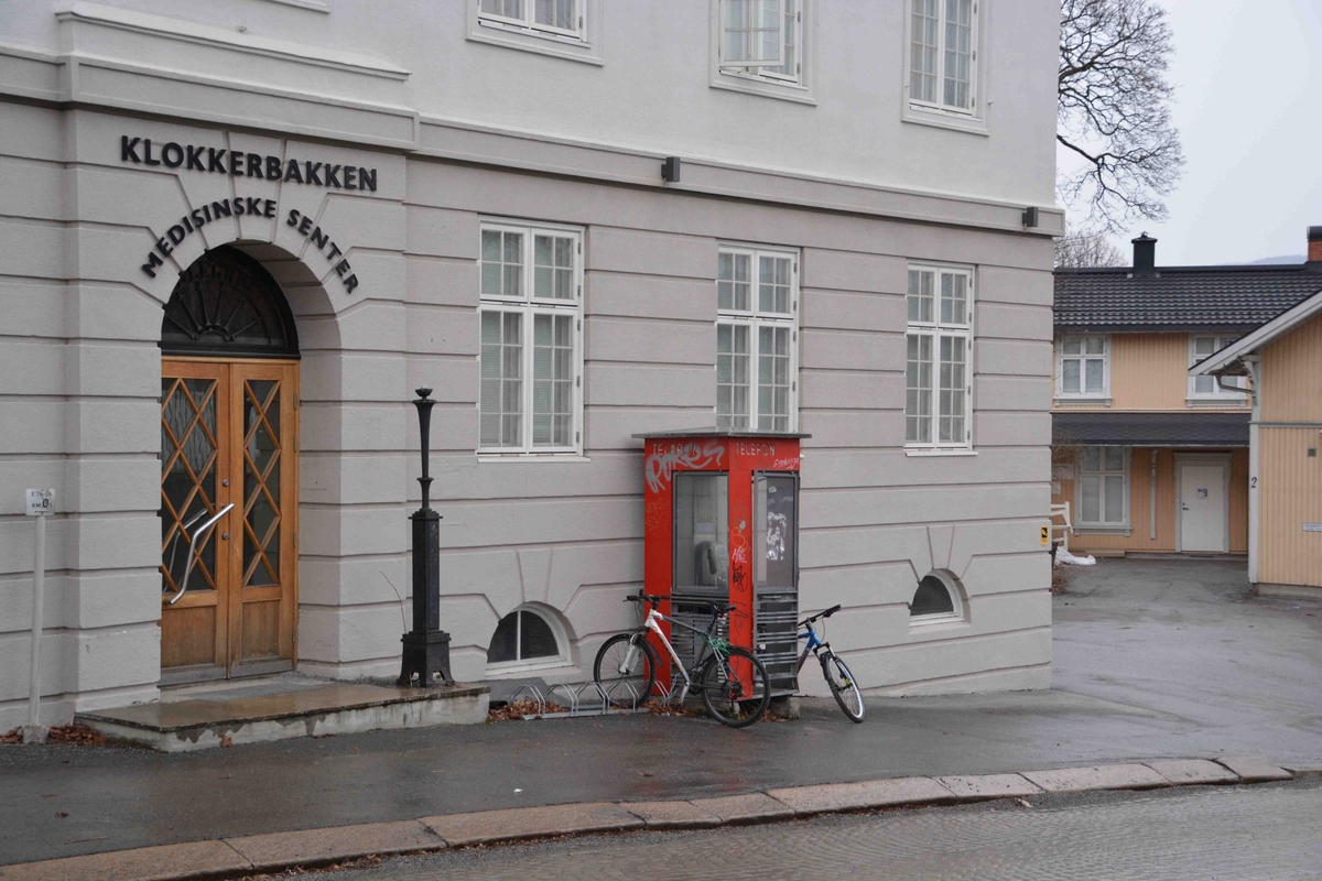 This is the story of how Norway’s most important conversation-space was designed by a young, freshly graduated man from Bergen.

“Norwegian architects are hereby invited…”
In the autumn of 1932, Oslo Telefonanlegginitiated an architectural competition. Finally, Oslo would get its own telephone booth. The city had had so called “talking-stations” from 1885, which in turn were overtaken by automatic telephones 
 only available at selected Narvesen kiosks. The state 
was of the opinion that now was the time to offer the public a better service; public telephone booths open 24/7, like the ones they already had in Sweden and England. But what would they look like, these new telephone booths? What considerations would it
 be necessary to take when designing it? The telegraph board developed a detailed list of demands and restraints: “The booth is intended to be placed outside on the streets and squares and need to be designed so that snow and ice does not hinder the opening and closing of the doors,” they wrote. “To prevent vandalism, theft, uncleanliness etc. inside the booth, it needs to be designed so that from all angles one may see what is going on in there.” Additionally, it would need to withstand storms and bad weather, and “preferably also being whipped by rain mixed with seawater” 

This was not all: The appearance would have to be «pleasing». The booth also needed to be movable, so that it could be taken in to be serviced at Telegrafverket’s main workshops. The reqired material was iron, and the surface was to be spray painted  preferably using car-body paint. There was a requirement for “a writing shelf, a pack shelf, and a suitable place for the telephone catalogue.” Also, there would need to be an illuminated TELEFON  sign, easily visible from all four angles. The total cost for each booth should not exceed 1000 kroner. The first prize for coming up with such a product was 800 kroner.

“Norwegianarchitects are hereby invited to partake in a competition for the design of a telephone booth…”  

The man with the solution
«At some point in 1932, Georg Fredrik sat at a party in Bergen. Maybe he felt a bit lost and forgotten as he often had throughout his life. He retreated to a quiet corner, took out a pencil and strted doodling on a matchbox.  According to my mother, this was how the telephone booth came into being.” In the book “Norges lille røde  historien om telefonkiosken,” Lars Fasting describes his father, the man who is far less known than the iconic architctural structure he left behind. Georg Fredrik Fasting was from Bergen, born into a family of working people and smallholders. One unusual facet of Georg Fredrik was that he was born without ears. His mother made sure he learnt to speak, read and write, 
ut Lars Fasting indicates that his father would seek refuge in drawing when the social challenges became too much to bear. And in the end drawing became his profession. In 1924 he secured a guarantor for a student loan, and started studying to become an a
rchitect at the NTH. Throughout the 1930s he entered several architectural competitions, with drafts produced, according to his son, “after work and in the late hours of the night.”

His efforts were not wasted. Out of 93 entries, with names such as “Flirt”, “Brrr”, “Ring” and “Amor”, the jury selected Fasting’s submission, “RIKS” as the new telephone booth: “The draft shows a strikingly simple solution to the task, technically as well as aesthetically well worked out.”

Taut and provident
Simple and aesthetc are the keywords here. Fasting had designed a booth pointing towards the future, and to modernism. Just how modern it was can be seen by comparing RIKS to the British telephone booth, also designed in the interwar-era. While the British version with it classicistic style is looking back to the heyday of the empire, Fasting’s booth is progressive and functionalistic. Like most Norwegian architects, Fasting broke with the classicistic style of architecture after the Stockholm-exhibition in 1930. “After it, almost all buildings erected in Norway until the German invasion in 1940, were in the functionalistic architectural style,” writes senior curator of architecture at the Norwegian National Museum, Ulf Grønvold, in the book, “Den lille røde”.“TheNorwegian booth is a piece of functionalistic architecture, an asymmetric composition with its roof slab overhanging the word TELEFON, in bold sans seraph lettering,”concludes Ulf Grønvold.

Fashionably red
And it was red. Fasting chose a colour which was part of the modern palette. “A bright red colour, but not as shiny as a signal red, the character of the colour places it among the fashionable colours within functionalism,” states paintings conservator and researcher in NIKU (Norwegian Institute for Cultural Heitage Research), Jon Brænne. In his opinion, Fasting went for visibility without making the booth stand out too much from its surroundings. The original colour was in use up to around 1950, when it changed to signal red. Towards the end of the 1970s the clour was again adjusted towards today’s orangey red.

The design, however, has not changed. RIKS is eighty years and still looks remarkably good. That’s what makes Fasting’s telephone booth a classic  even before it was added to DOCOMOMO’s list over moden icons of design. For Telenor, the telephone booth has served as a pathway into the hearts of the public. For many, Telenor (Televerket) was synonymous with exactly this telephone booth, because this was where one would go to place a call. Having a home
phone was not common until the 1980s. As such the red box became part of the Norwegian everyday and consciousness. The symbol- and publicity value of this is hard to evaluate, but in 2007 it was time to give honour where honour was due, Telenor, in consul
tation with the Directorate for Cultural Heritage, decided to preserve 100 telephone booths for all eternity.

And what about Georg Fredrik Fasting? What happened to him? At the age of 56 an entry in his diary states: «I CAN HEAR». As the first person in th world he had undergone an operation where he had ear canals constructed and eardrums fitted. For the rest of his life, the man behind Norway’s own telephone booth could answer the telephone himself.

Source: Norges lille røde historien om telefonkiosken (2007), issued by The Norwegian Telecom Museum and Telenor Cultural Heritage.