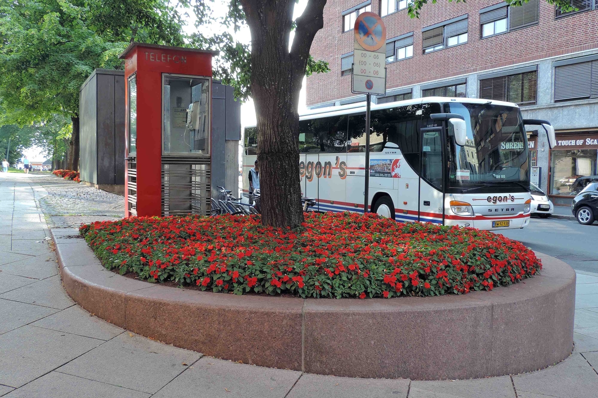This is the story of how Norway’s most important conversation-space was designed by a young, freshly graduated man from Bergen.

“Norwegian architects are hereby invited…”
In the autumn of 1932, Oslo Telefonanlegginitiated an architectural competition. Finally, Oslo would get its own telephone booth. The city had had so called “talking-stations” from 1885, which in turn were overtaken by automatic telephones 
 only available at selected Narvesen kiosks. The state 
was of the opinion that now was the time to offer the public a better service; public telephone booths open 24/7, like the ones they already had in Sweden and England. But what would they look like, these new telephone booths? What considerations would it
 be necessary to take when designing it? The telegraph board developed a detailed list of demands and restraints: “The booth is intended to be placed outside on the streets and squares and need to be designed so that snow and ice does not hinder the opening and closing of the doors,” they wrote. “To prevent vandalism, theft, uncleanliness etc. inside the booth, it needs to be designed so that from all angles one may see what is going on in there.” Additionally, it would need to withstand storms and bad weather, and “preferably also being whipped by rain mixed with seawater” 

This was not all: The appearance would have to be «pleasing». The booth also needed to be movable, so that it could be taken in to be serviced at Telegrafverket’s main workshops. The reqired material was iron, and the surface was to be spray painted  preferably using car-body paint. There was a requirement for “a writing shelf, a pack shelf, and a suitable place for the telephone catalogue.” Also, there would need to be an illuminated TELEFON  sign, easily visible from all four angles. The total cost for each booth should not exceed 1000 kroner. The first prize for coming up with such a product was 800 kroner.

“Norwegianarchitects are hereby invited to partake in a competition for the design of a telephone booth…”  

The man with the solution
«At some point in 1932, Georg Fredrik sat at a party in Bergen. Maybe he felt a bit lost and forgotten as he often had throughout his life. He retreated to a quiet corner, took out a pencil and strted doodling on a matchbox.  According to my mother, this was how the telephone booth came into being.” In the book “Norges lille røde  historien om telefonkiosken,” Lars Fasting describes his father, the man who is far less known than the iconic architctural structure he left behind. Georg Fredrik Fasting was from Bergen, born into a family of working people and smallholders. One unusual facet of Georg Fredrik was that he was born without ears. His mother made sure he learnt to speak, read and write, 
ut Lars Fasting indicates that his father would seek refuge in drawing when the social challenges became too much to bear. And in the end drawing became his profession. In 1924 he secured a guarantor for a student loan, and started studying to become an a
rchitect at the NTH. Throughout the 1930s he entered several architectural competitions, with drafts produced, according to his son, “after work and in the late hours of the night.”

His efforts were not wasted. Out of 93 entries, with names such as “Flirt”, “Brrr”, “Ring” and “Amor”, the jury selected Fasting’s submission, “RIKS” as the new telephone booth: “The draft shows a strikingly simple solution to the task, technically as well as aesthetically well worked out.”

Taut and provident
Simple and aesthetc are the keywords here. Fasting had designed a booth pointing towards the future, and to modernism. Just how modern it was can be seen by comparing RIKS to the British telephone booth, also designed in the interwar-era. While the British version with it classicistic style is looking back to the heyday of the empire, Fasting’s booth is progressive and functionalistic. Like most Norwegian architects, Fasting broke with the classicistic style of architecture after the Stockholm-exhibition in 1930. “After it, almost all buildings erected in Norway until the German invasion in 1940, were in the functionalistic architectural style,” writes senior curator of architecture at the Norwegian National Museum, Ulf Grønvold, in the book, “Den lille røde”.“TheNorwegian booth is a piece of functionalistic architecture, an asymmetric composition with its roof slab overhanging the word TELEFON, in bold sans seraph lettering,”concludes Ulf Grønvold.

Fashionably red
And it was red. Fasting chose a colour which was part of the modern palette. “A bright red colour, but not as shiny as a signal red, the character of the colour places it among the fashionable colours within functionalism,” states paintings conservator and researcher in NIKU (Norwegian Institute for Cultural Heitage Research), Jon Brænne. In his opinion, Fasting went for visibility without making the booth stand out too much from its surroundings. The original colour was in use up to around 1950, when it changed to signal red. Towards the end of the 1970s the clour was again adjusted towards today’s orangey red.

The design, however, has not changed. RIKS is eighty years and still looks remarkably good. That’s what makes Fasting’s telephone booth a classic  even before it was added to DOCOMOMO’s list over moden icons of design. For Telenor, the telephone booth has served as a pathway into the hearts of the public. For many, Telenor (Televerket) was synonymous with exactly this telephone booth, because this was where one would go to place a call. Having a home
phone was not common until the 1980s. As such the red box became part of the Norwegian everyday and consciousness. The symbol- and publicity value of this is hard to evaluate, but in 2007 it was time to give honour where honour was due, Telenor, in consul
tation with the Directorate for Cultural Heritage, decided to preserve 100 telephone booths for all eternity.

And what about Georg Fredrik Fasting? What happened to him? At the age of 56 an entry in his diary states: «I CAN HEAR». As the first person in th world he had undergone an operation where he had ear canals constructed and eardrums fitted. For the rest of his life, the man behind Norway’s own telephone booth could answer the telephone himself.

Source: Norges lille røde historien om telefonkiosken (2007), issued by The Norwegian Telecom Museum and Telenor Cultural Heritage.