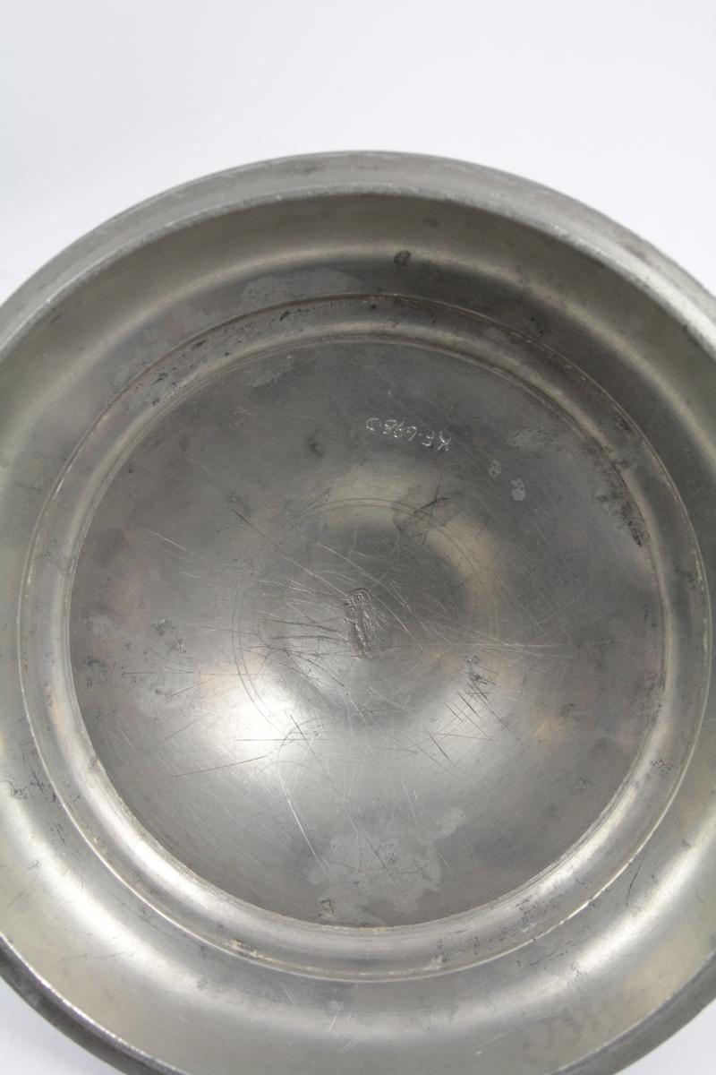 Matspann av fire deler og bærerem. 

a: Beholder. Nederste. Sirkelrund bunn med lav fotring, utbuket side, innsnevret rand. To bøyleformede hanker over snelleformet knapp. 

b: Beholder. Midtre. Sirkelrund. Svakt hvelvet bunn, med horisontal kant. vertikal side profilert ved kanten, og forsynt med to rettvinklede ører. 

c: Beholder. Som b. 

d: Lokk. Sirkelrundt, hvelvet, prydet med to konsentriske linjer, horisontal kant og dreiet knapp av tinn og tre. 

e: Rem. til å bære og forbinde delene. Lær, brun, flat med fire spaltelignende hull.