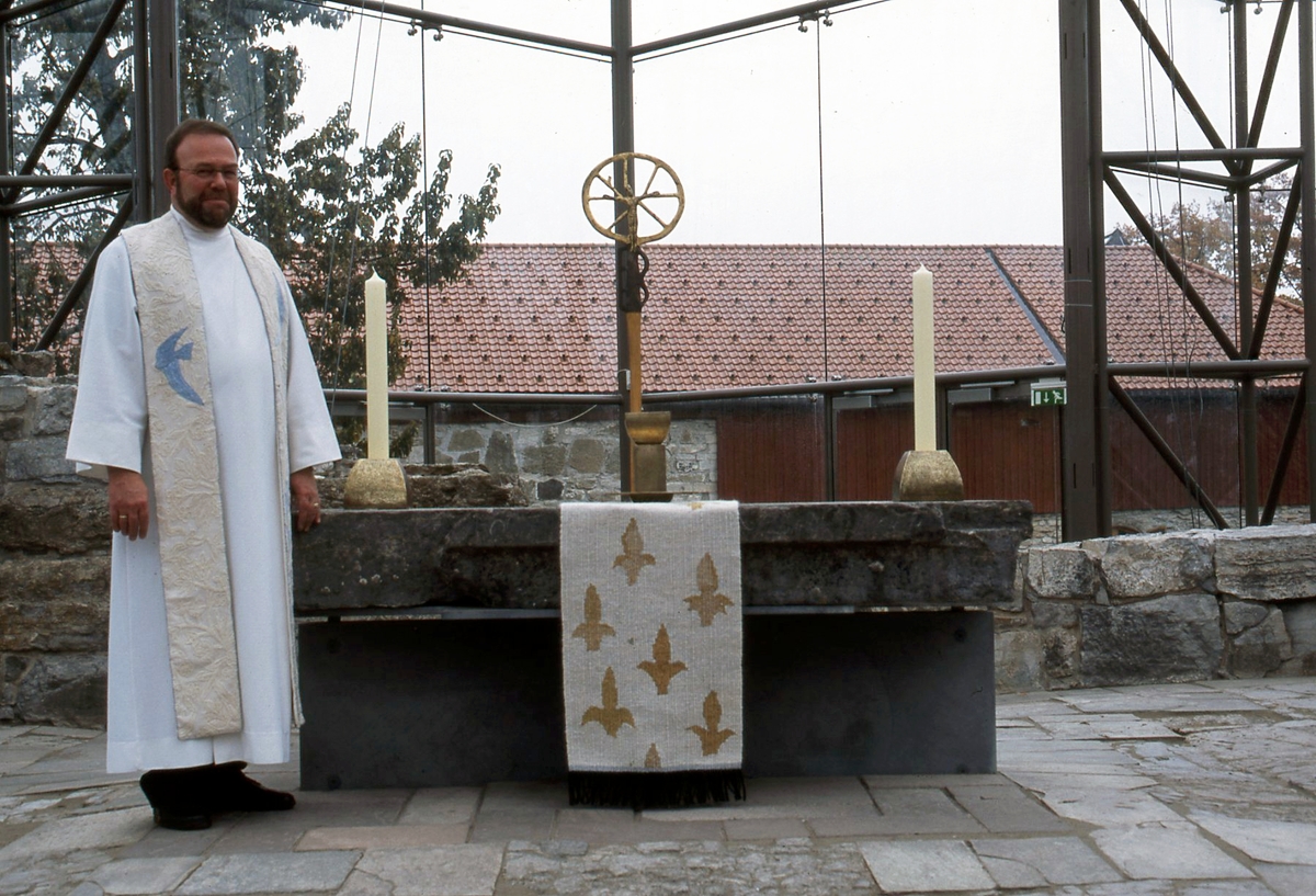 Ett av tre verk. Håndvevet bomull i naturhvitt med ullbroderier i naturhvitt. Broderiet er utført i moulinegarn i ulike blåfarger, sølv og gulltråd. 
Duen er det viktigste symbolet på den Hellige Ånd og den eneste fuglen som ble brukt ved de gammeltestamentlige ofringene.
Blått er himlens og havets farge, og leder tanken hen på det overjordiske, det guddommelige, på himlen og trofastheten. 
Gull betyr overjordisk storhet, og fargen anvendes derfor ofte som bakgrunn på bilderav hellige personer.